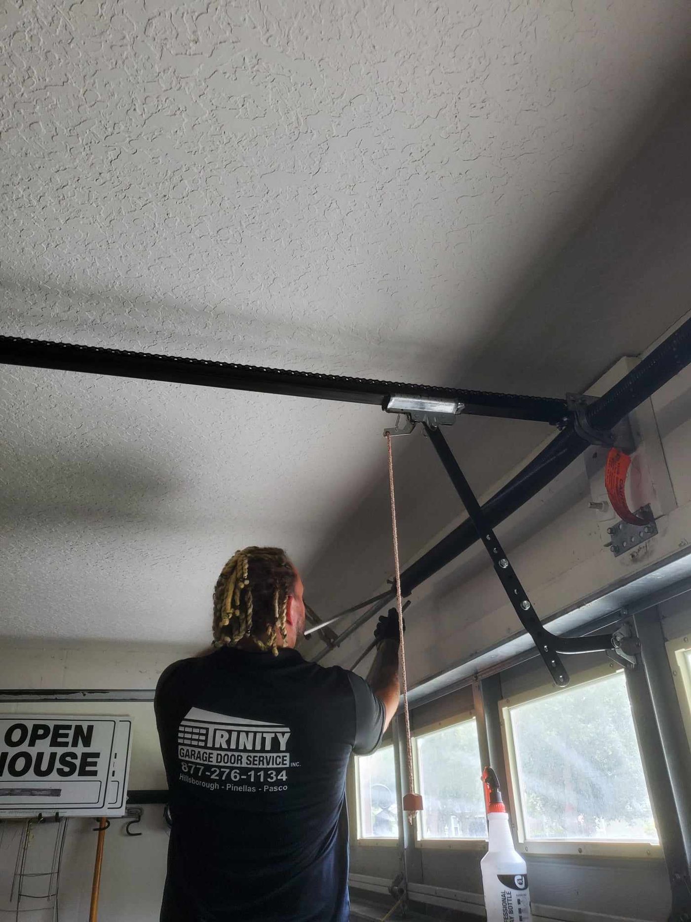 Trinity technician lubricating garage door hardware