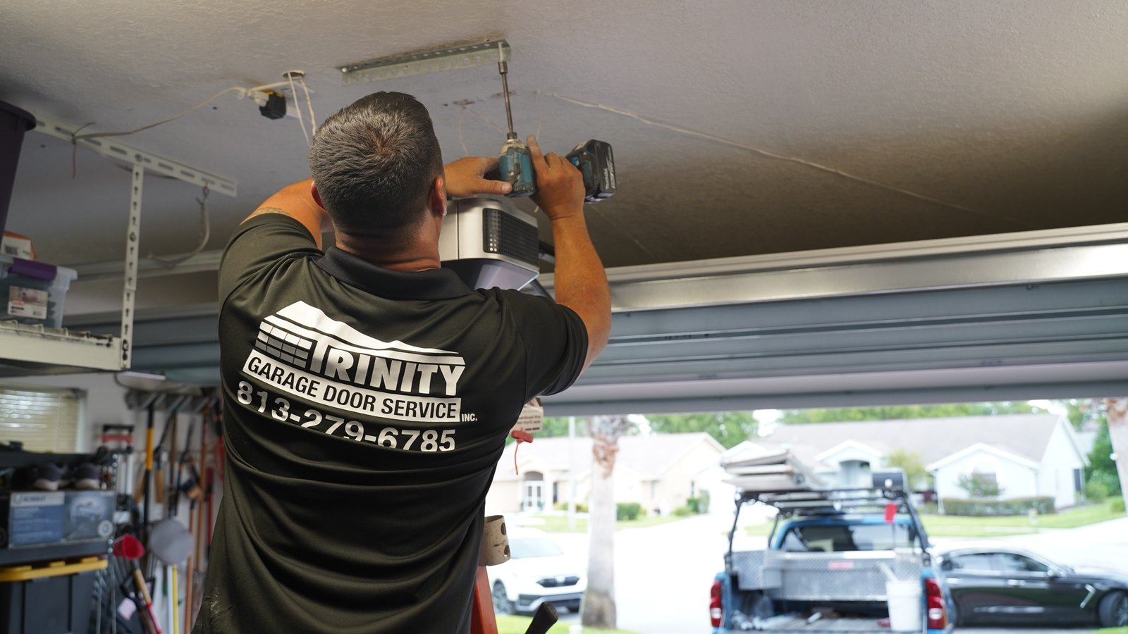 A Trinity technician mounting a garage door opener motor to the ceiling of a Florida garage
