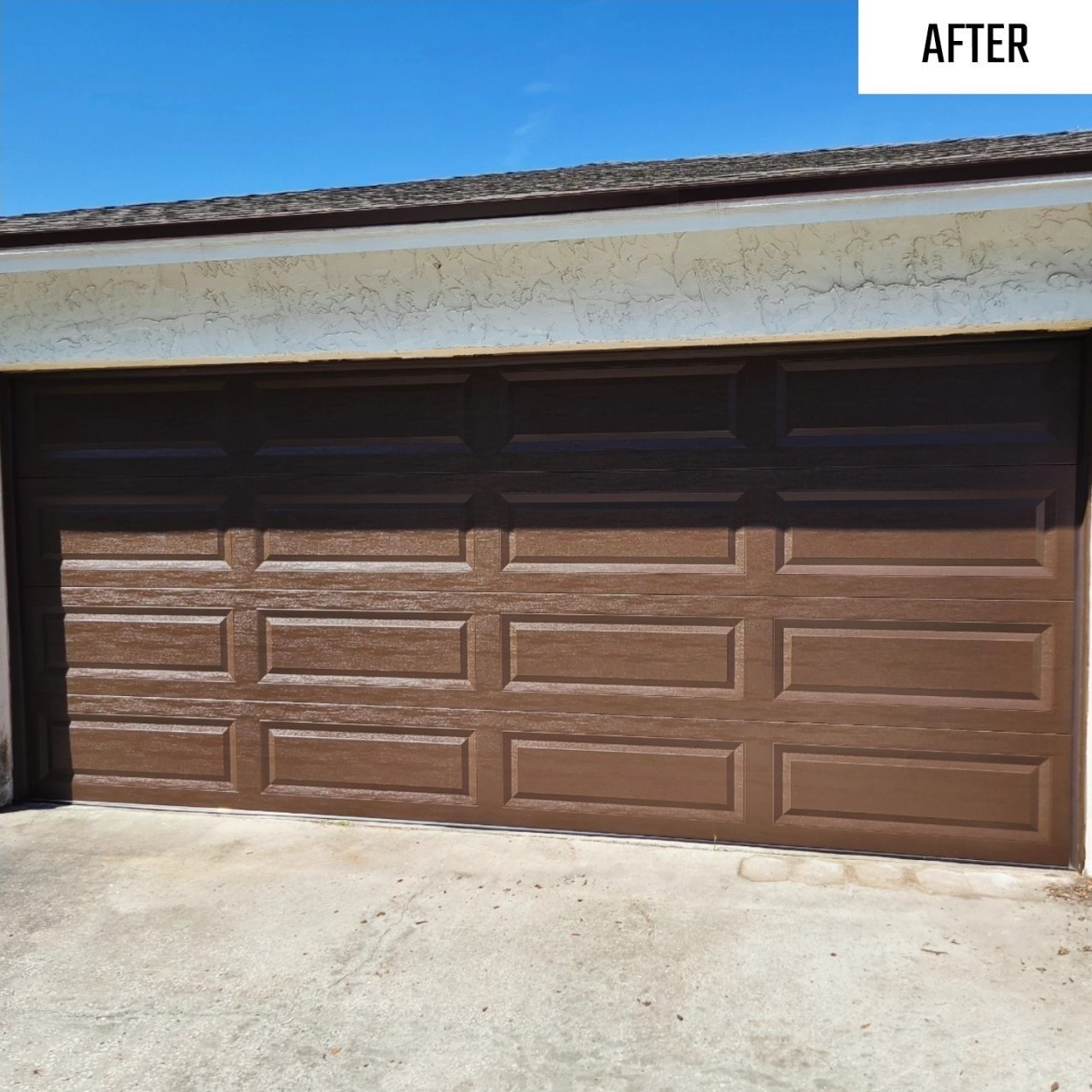 A wide brown raised panel garage door on a brick home