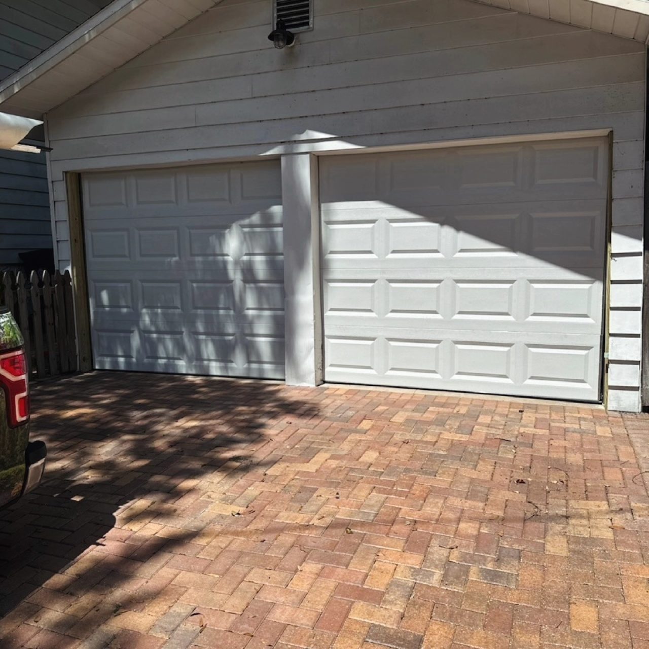 A white two car garage door above a brick paver driveway