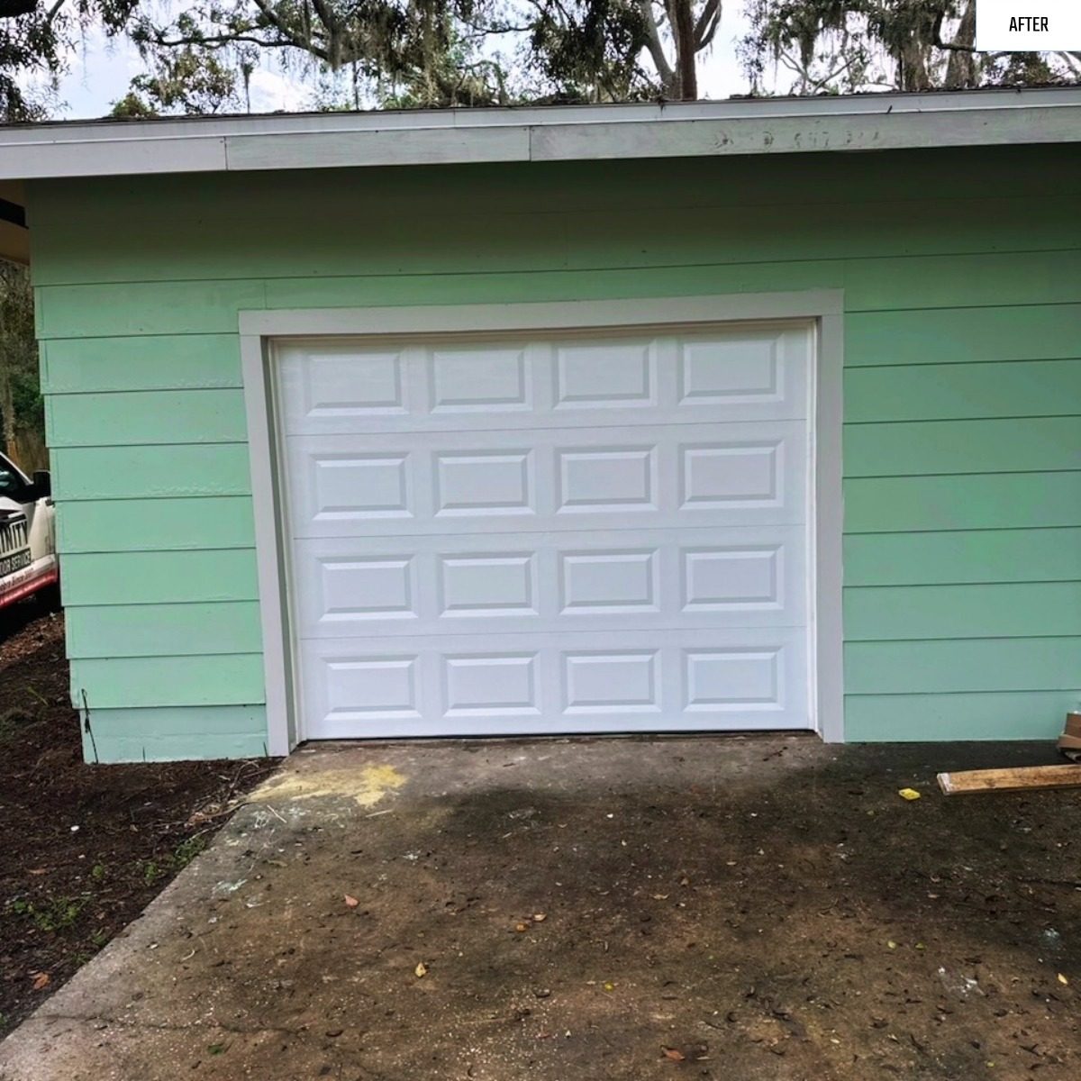 A new white garage door on a green sided home