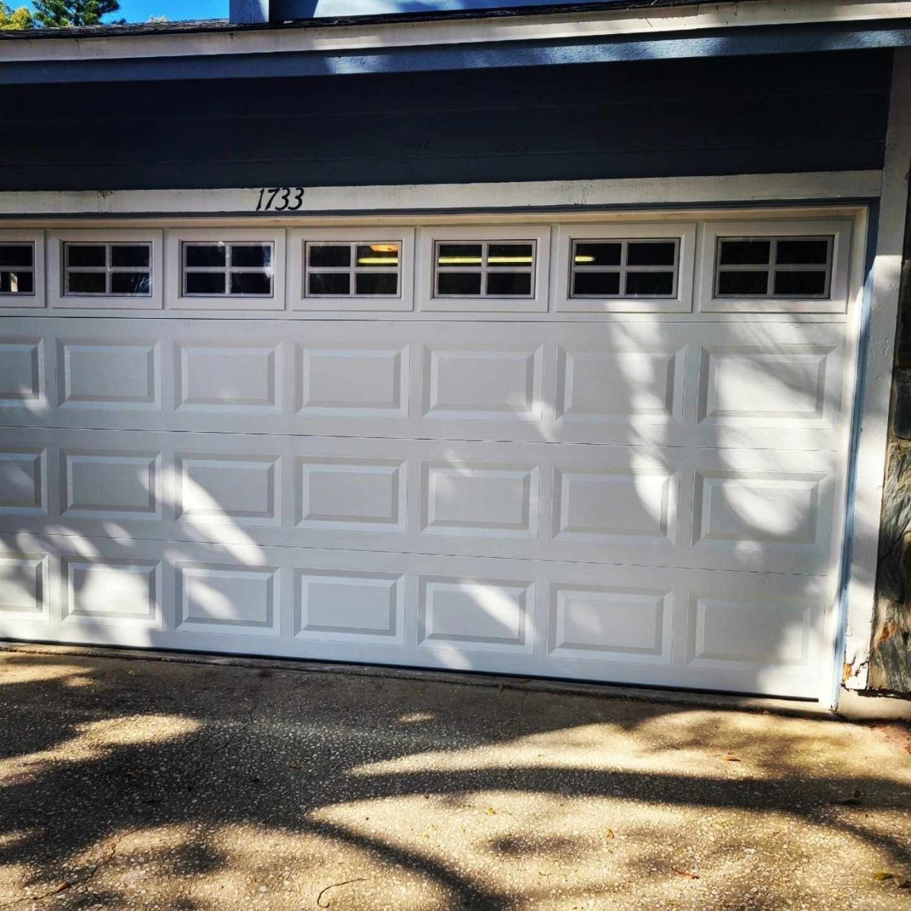 A white garage door with a row of windows across the top panel