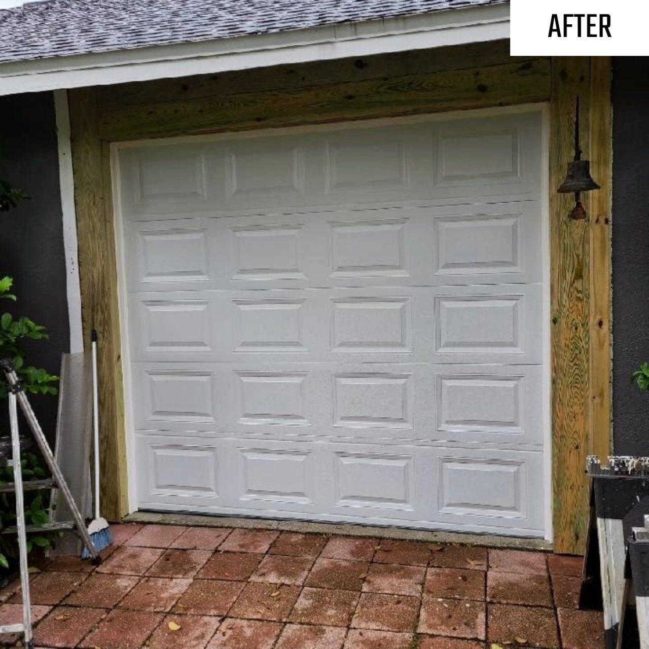 A white garage door fitted into a timber framed opening